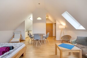 Un moderno loft con zona pranzo, divano, letto e finestra a lucernario.