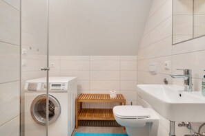 Un bagno compatto con lavatrice, WC e lavandino.