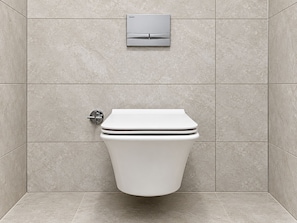 A modern bathroom with a toilet, a wall-mounted flush valve, and a control panel. - Kasr'ı Cihan Hotel (Midyat)