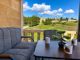 Varanda com vista para um edifício histórico e vegetação.