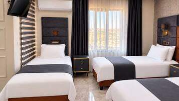 A hotel room with two beds, a flat-screen TV mounted on the wall, a large window with curtains, and a modern ceiling design.