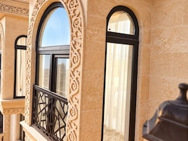 Fachada de edificio con ventanas arqueadas y detalles de piedra decorativa.