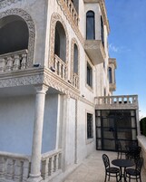 A building with ornate architectural details, including columns and arches, and a patio area with outdoor seating.
