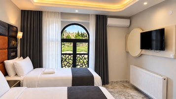 Quarto de hotel com duas camas, televisão e varanda com vista pela janela.