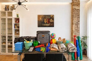 A living room with a glass coffee table, a white cabinet, a painting on the wall, and a brick column. - Cozy and spacious flat in the heart of Russafa (València)