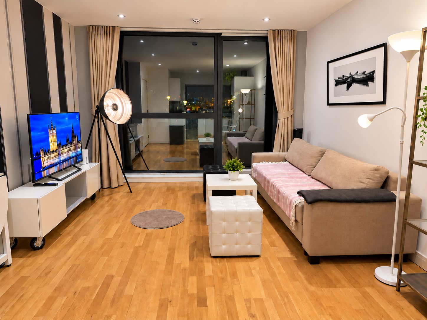 A modern living room with a flat-screen TV, a sofa, a coffee table, and a floor lamp.