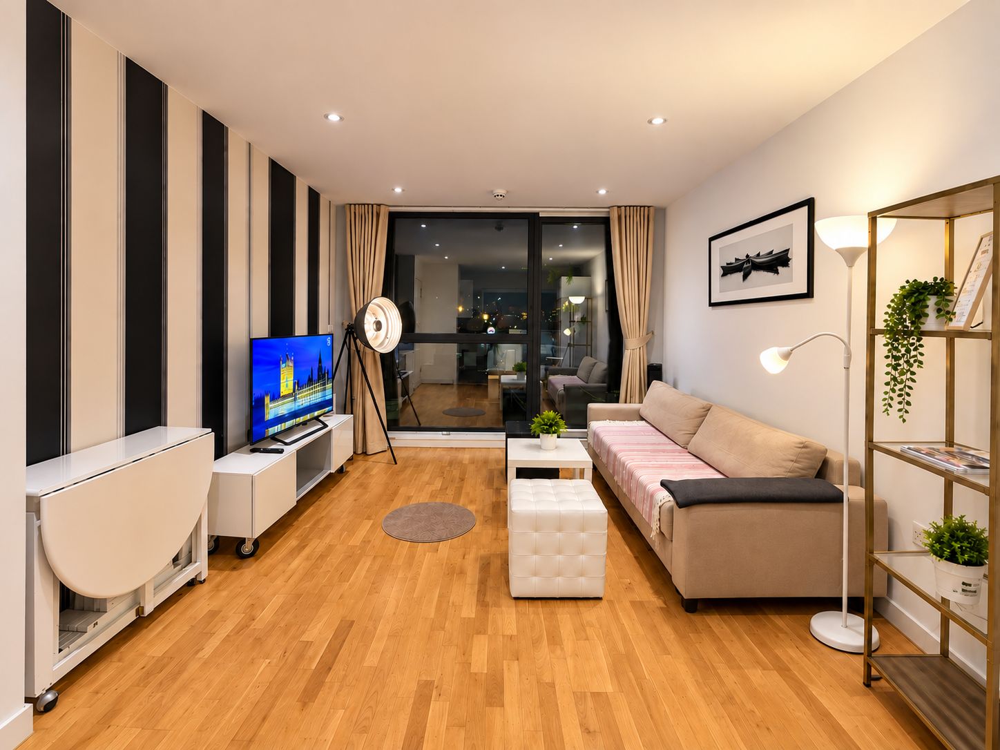 A modern living room with a flat-screen TV, a sofa, a coffee table, and a floor lamp.
