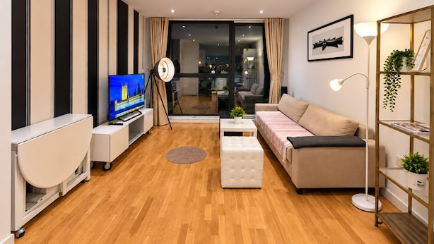 Una sala de estar moderna con un televisor de pantalla plana, un sofá, una mesa de centro y una lámpara de pie.