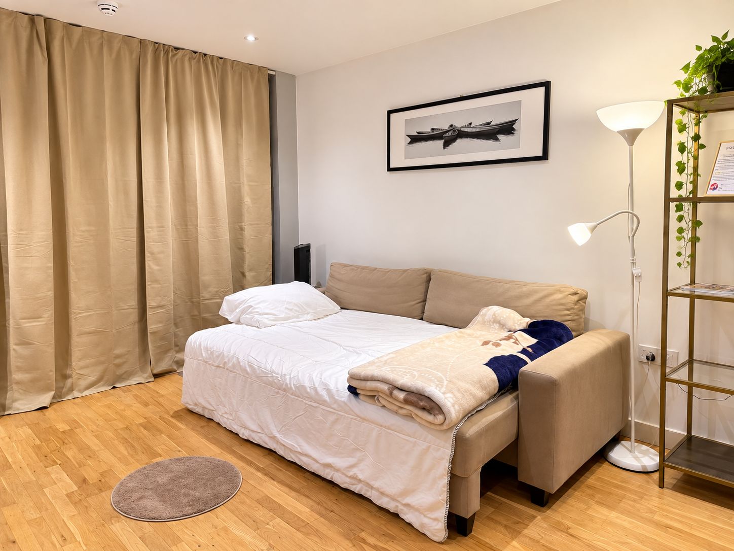 A neatly arranged bedroom with a bed, a bedside table, a lamp, and a framed picture on the wall.