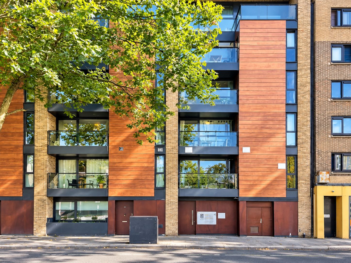 A multi-story building with a mix of brick and wooden facade, large windows, and balconies.