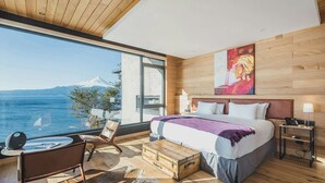 Een moderne slaapkamer met een groot raam, een bed, een bureau en uitzicht op een berg.