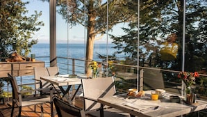 An outdoor dining area with a table set for two, overlooking a body of water and trees. - Hotel Awa (Puerto Varas)