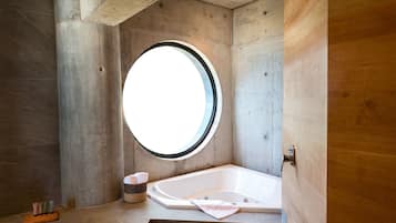 A bathroom with a bathtub, a round window, and a wooden door.