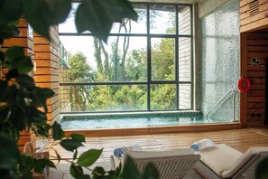 A spa area with a large window, wooden flooring, and a hot tub. - Hotel Awa (Puerto Varas)