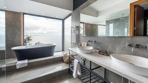 A modern bathroom with a freestanding bathtub, two sinks, and a large mirror. - Hotel Awa (Puerto Varas)