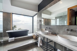 A modern bathroom with a freestanding bathtub, two sinks, and a large mirror. - Hotel Awa (Puerto Varas)