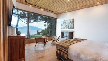 Un dormitorio con una ventana grande, una chimenea y vistas a un lago.
