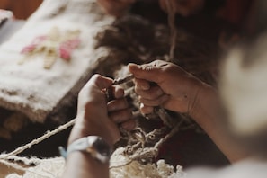 Hands holding a piece of yarn, suggesting a crafting activity. - Hotel Awa (Puerto Varas)