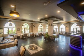 A spacious dining area with tables, chairs, and large windows. - Buyuk Mardin (Mardin)