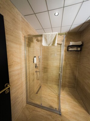 A glass-enclosed shower stall with a towel hanging on the door, a towel rack above, and a control panel on the wall. - Buyuk Mardin (Mardin)