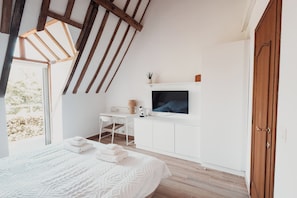 Een slaapkamer met een bed, een bureau, een televisietoestel en een kledingkast.