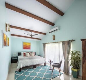 A bedroom with a bed, a ceiling fan, an air conditioner, a window with curtains, a small table, a chair, and a potted plant. - ama Stays & Sluice House Lonavala (Mawal)