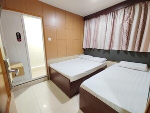 A hotel room with two beds, a sliding door, and a patterned curtain.