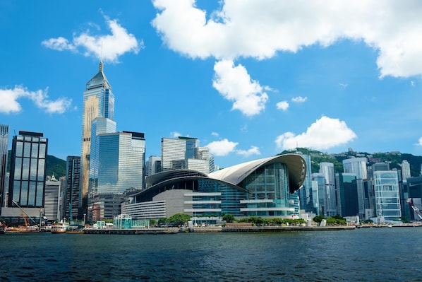 A modern city skyline with prominent skyscrapers and a distinctive curved building near a waterfront. - HOO Sang Hotel (Kowloon)