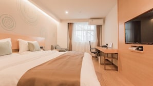 Een hotelkamer met een bed, een bureau, een stoel, een televisie en een airconditioning.