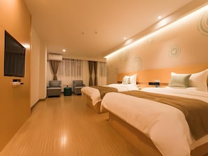 Ein Hotelzimmer mit zwei Betten, einer Sitzecke mit Stühlen, einem Fernseher und einer Klimaanlage.