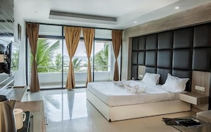 A modern hotel room with a large bed, a flat-screen TV, and a balcony with curtains. - Hotel Sonar Bangla Mandarmoni (Kanthi)