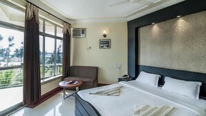 Une chambre d’hôtel avec un lit, une chaise, une petite table et une grande fenêtre.