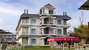 Un hôtel à plusieurs étages doté de balcons, d’un espace extérieur aménagé et situé dans un cadre tropical.