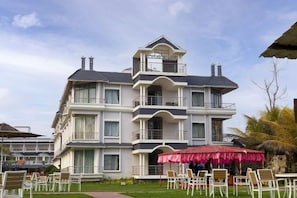 A multi-story hotel with balconies, outdoor seating, and a tropical setting. - Hotel Sonar Bangla Mandarmoni (Kanthi)