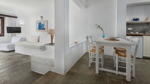 Ein moderner, minimalistischer Wohnraum mit einer Couch, einem Esstisch und einer Küchenzeile.