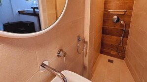Ein Badezimmer mit einem weißen Waschbecken, einem Spiegel und einer Duschkabine mit Holzverkleidung.