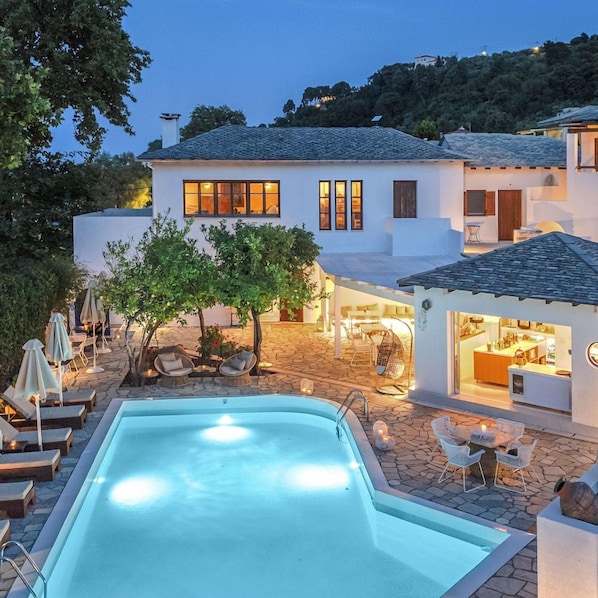 Una casa moderna con piscina, zona de estar al aire libre y barra.