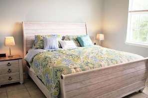 Un dormitorio con una cama de madera, una mesita de noche, una lámpara y una ventana.