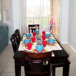Una mesa de comedor dispuesta con varios cuencos y tazas, rodeada de sillas.