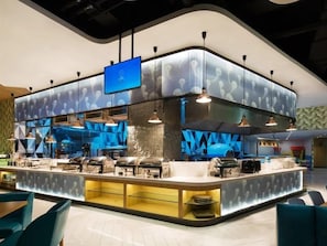 Un espace cuisine moderne doté d’un îlot central, d’un éclairage au plafond et d’un téléviseur à écran plat.