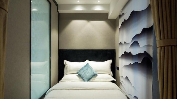 Ein Hotelzimmer mit einem Bett, einem Kopfteil und einer Wand mit wellenförmigem Design.