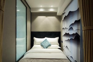 Una habitación de hotel con una cama, cabecera y pared con diseño ondulado.