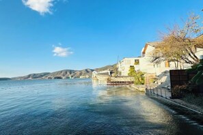 Ein Wohnhaus am Wasser mit Blick auf das Gewässer, ein Gebäude mit einem Balkon und einem klaren Himmel.
