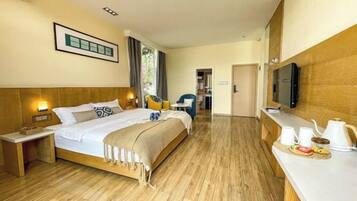 A hotel room with a large bed, bedside tables, a TV, and a breakfast bar.