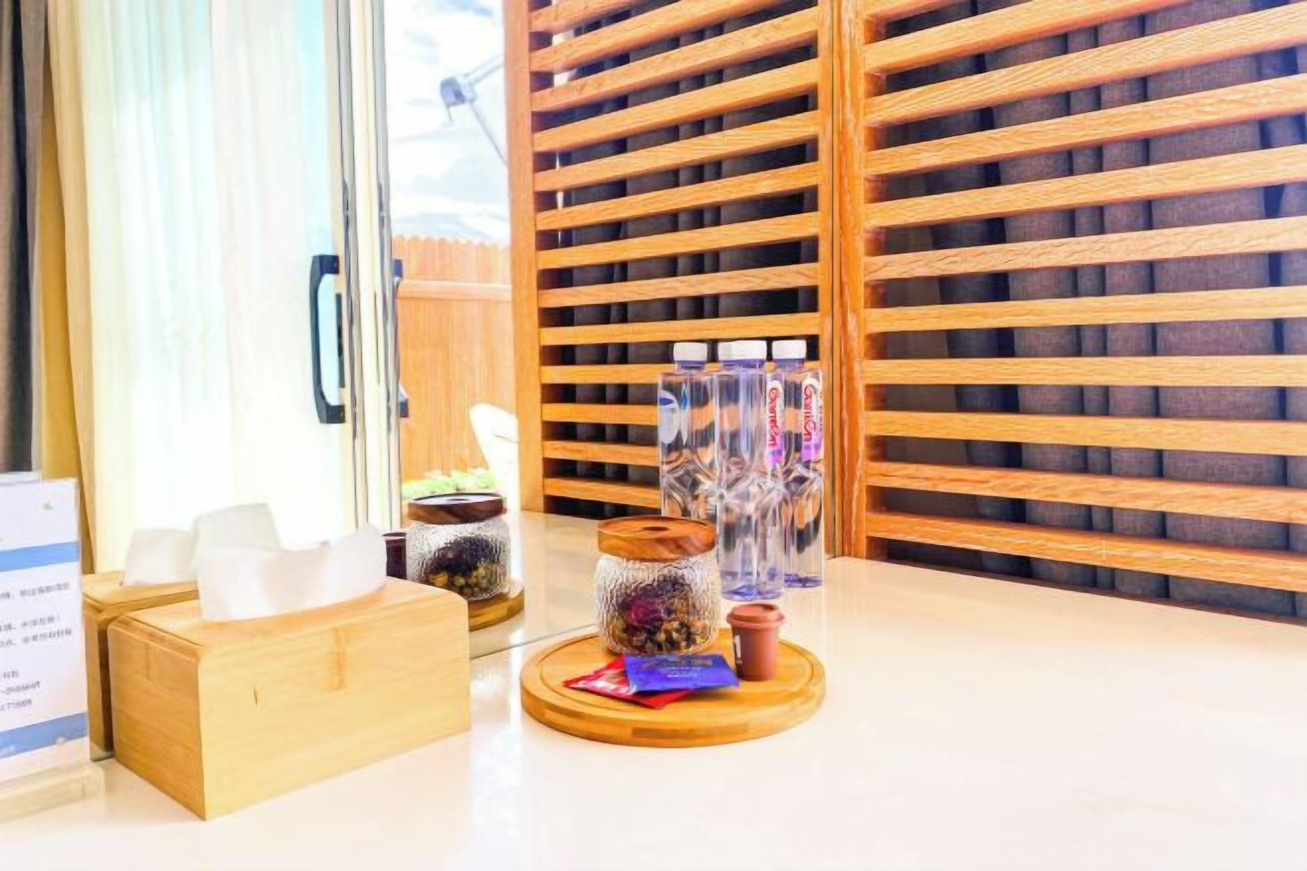 A hotel reception area with a wooden slatted wall, a reception desk, and a display of glass jars with items inside.