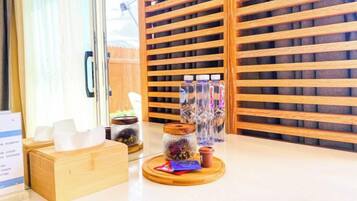 A hotel reception area with a wooden slatted wall, a reception desk, and a display of glass jars with items inside.