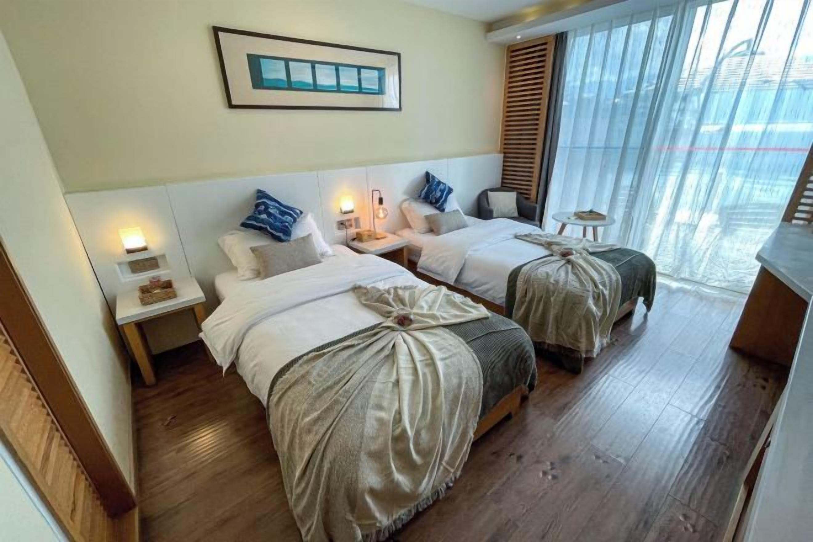 A hotel room with two beds, a small table, and a window with blinds.