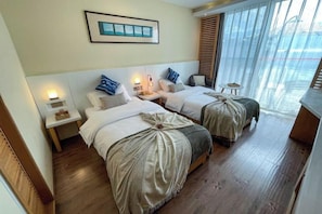 A hotel room with two beds, a small table, and a window with blinds.