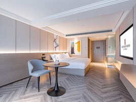 Una habitación de hotel moderna con una cama, una zona de estar con una mesa y un televisor.