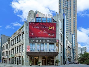A multi-story building with a prominent red advertisement on the facade. - Rezen Hotel Meiyo (Suining)